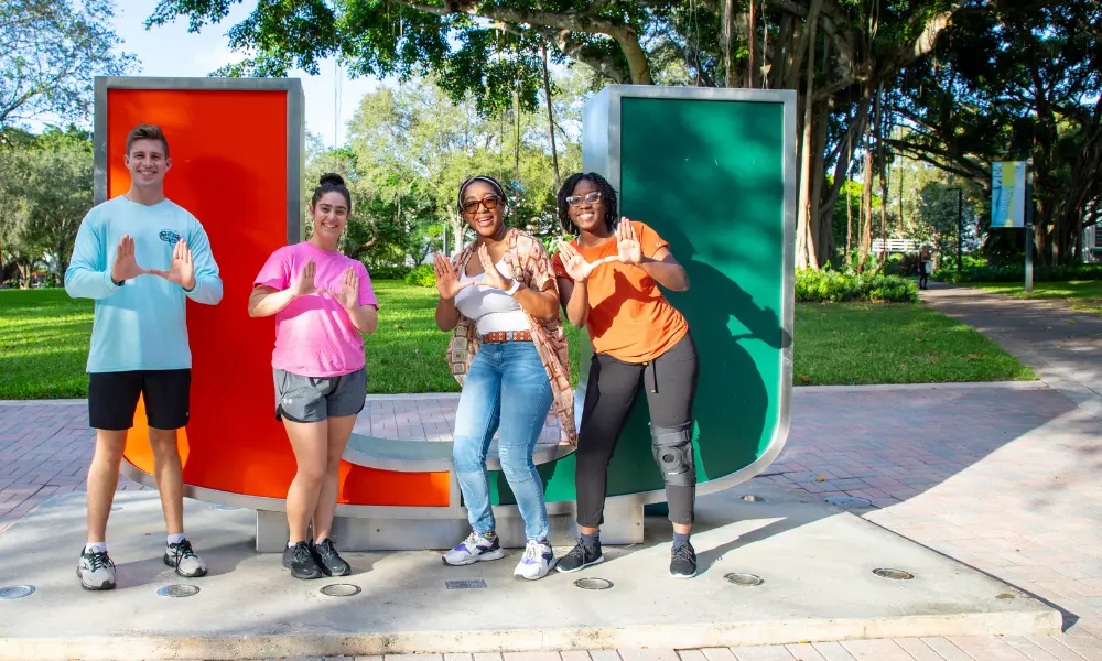 Students pose for a photo by the U statue